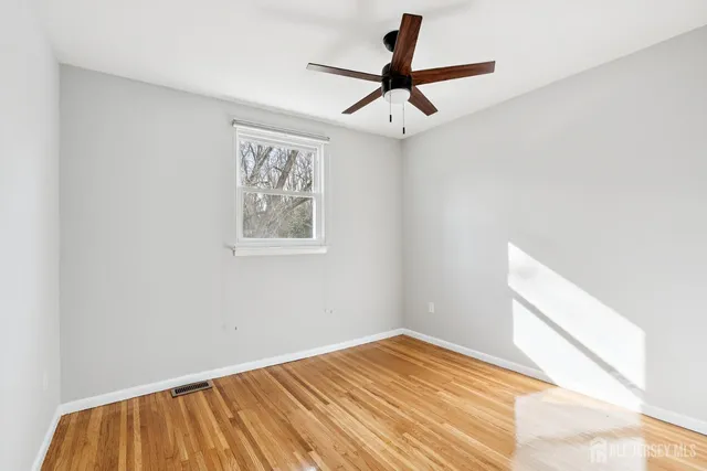 a view of a room with wooden floor and a ceiling fan