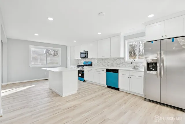 a kitchen with a refrigerator a sink cabinets and wooden floor