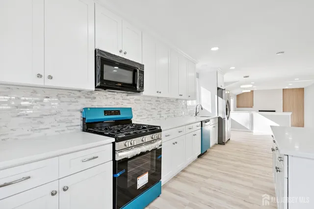 a kitchen with stainless steel appliances white cabinets a sink and a stove