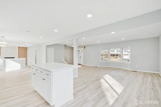 a view of a kitchen with kitchen island a sink wooden floor and living room view