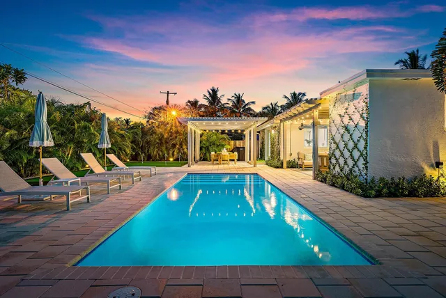 a view of a swimming pool with lawn chairs under an umbrella
