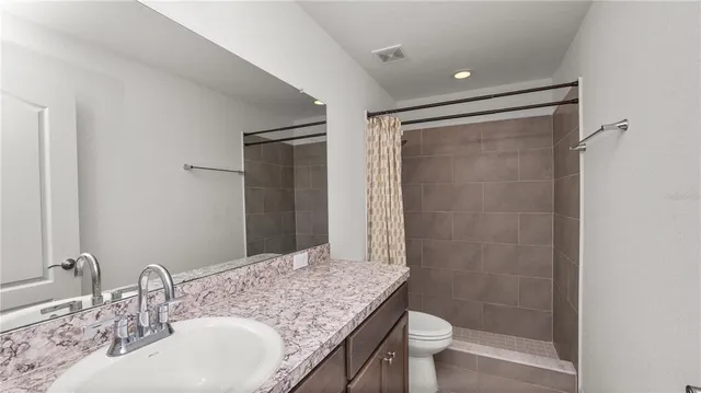 a bathroom with a granite countertop sink toilet and shower
