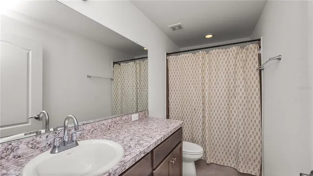 a bathroom with a granite countertop sink a toilet and a mirror
