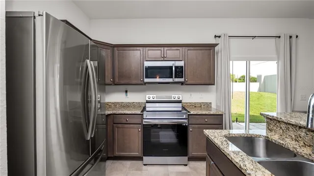 a kitchen with granite countertop a refrigerator stove and sink