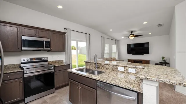 a kitchen with stainless steel appliances kitchen island granite countertop a sink stove and microwave