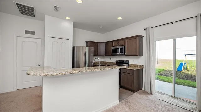 a kitchen with stainless steel appliances granite countertop a refrigerator a stove top oven a sink and dishwasher