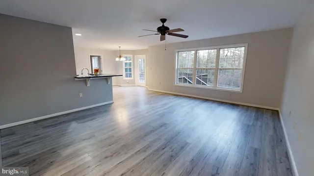 an empty room with wooden floor fan and windows