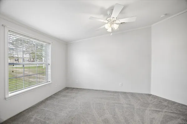 an empty room with windows and fan
