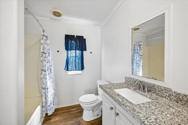 a bathroom with a granite countertop sink toilet and mirror