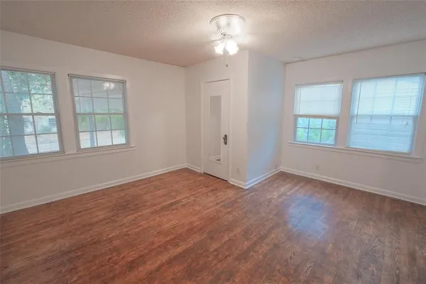 an empty room with wooden floor chandelier fan and windows