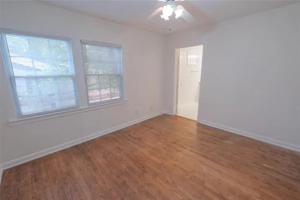 an empty room with chandelier fan and windows