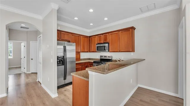 a kitchen with stainless steel appliances a refrigerator a sink dishwasher and wooden cabinets with wooden floor