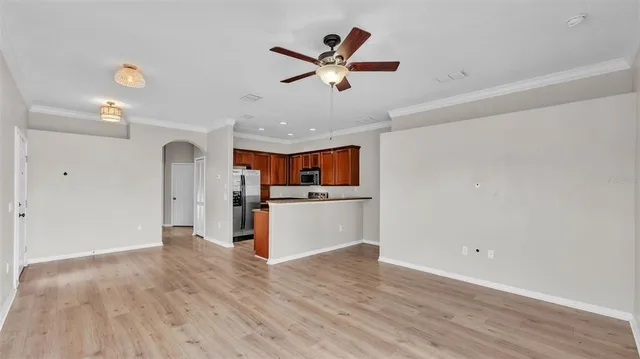 an empty room with wooden floor ceiling fan and window