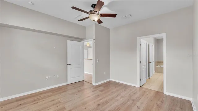a view of empty room with wooden floor and fan