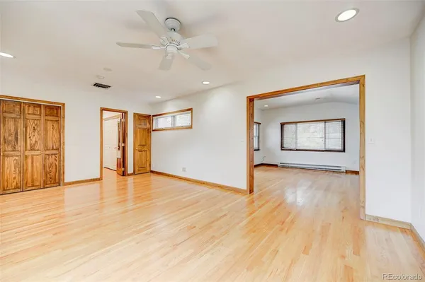 a view of an empty room with window and wooden floor