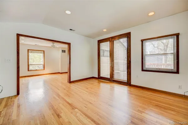 a view of an empty room with wooden floor and a window