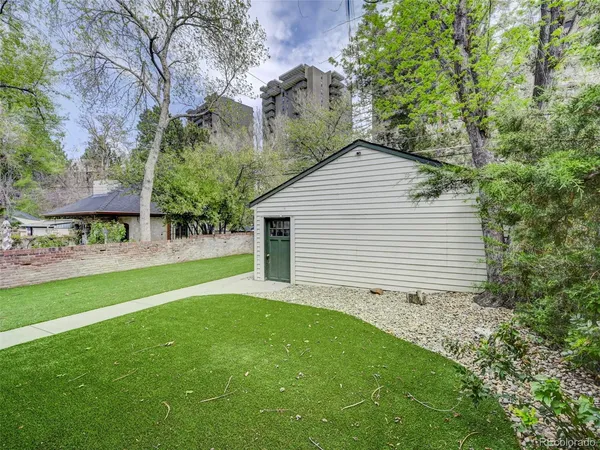 a backyard of a house with plants and large tree