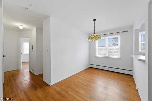 an empty room with wooden floor chandelier and windows