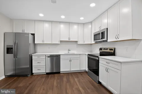 a kitchen with white cabinets white stainless steel appliances and sink