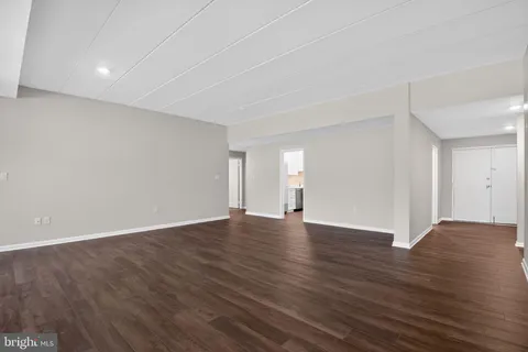 a view of an empty room with wooden floor and window