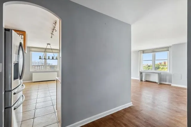a view of a hallway with wooden floor and a kitchen