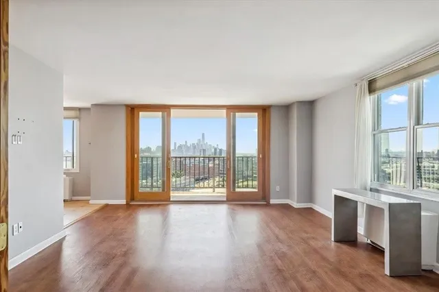 a view of an empty room with wooden floor and a window