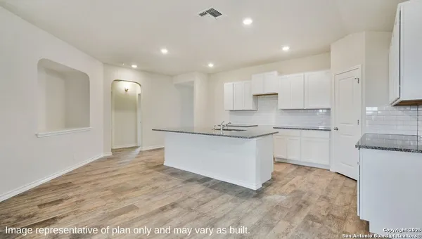 a large white kitchen with kitchen island a sink stainless steel appliances and cabinets