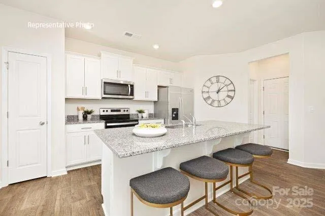 a kitchen with granite countertop a table chairs stove and cabinets