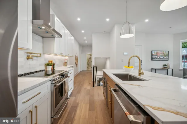 a kitchen with stainless steel appliances granite countertop a sink a stove and a wooden floors
