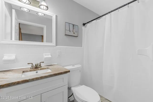 a bathroom with a granite countertop sink toilet and mirror