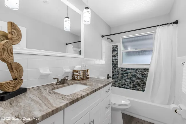 a bathroom with a granite countertop sink a toilet and shower