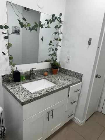 a bathroom with a granite countertop sink a mirror and shower