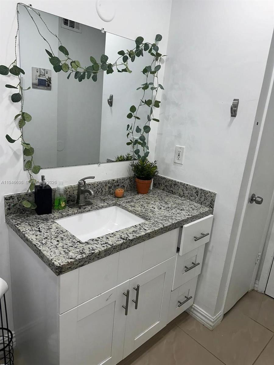 15560 Southwest 104th Terrace, Unit 6112 Miami, FL 33196 - Photo 11 of 12 a bathroom with a granite countertop sink a mirror and shower