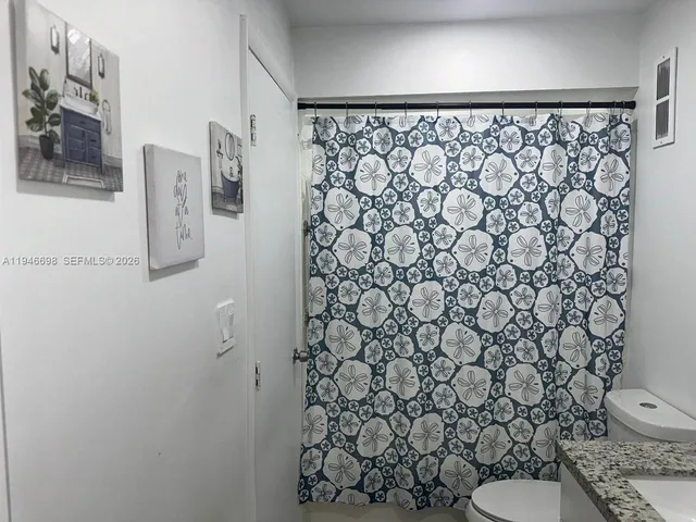 a white toilet sitting next to a shower curtain