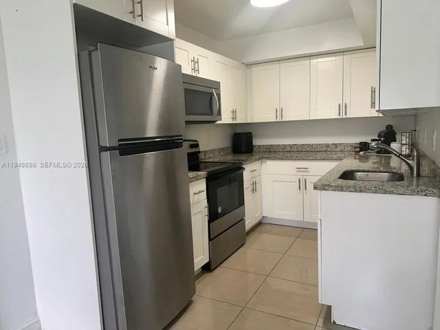 a kitchen with a refrigerator sink and cabinets