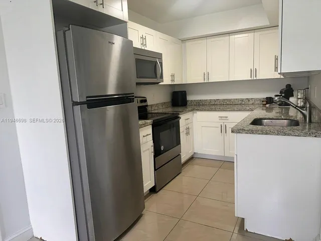 a kitchen with a refrigerator sink and cabinets