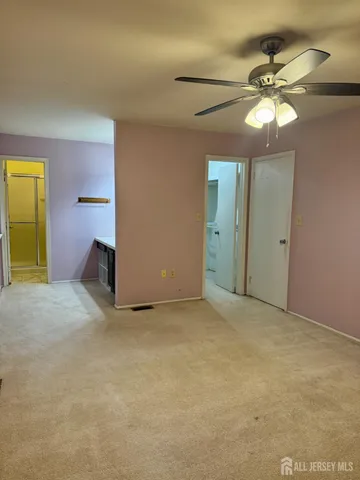 an empty room with a chandelier fan and a window