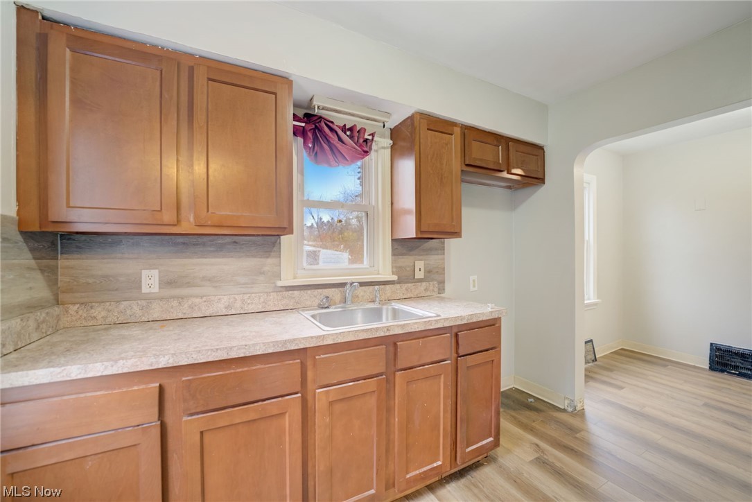 6106 Dunham Road Maple Heights, OH 44137 - Photo 10 of 23 Kitchen featuring sink, light wood-type flooring, and backsplash