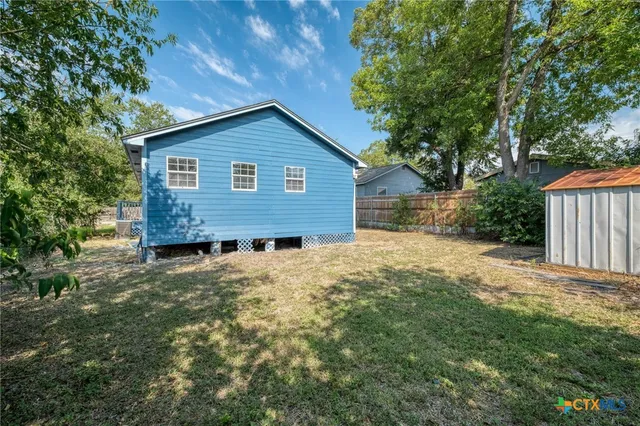 a view of a house with a yard and wooden fence