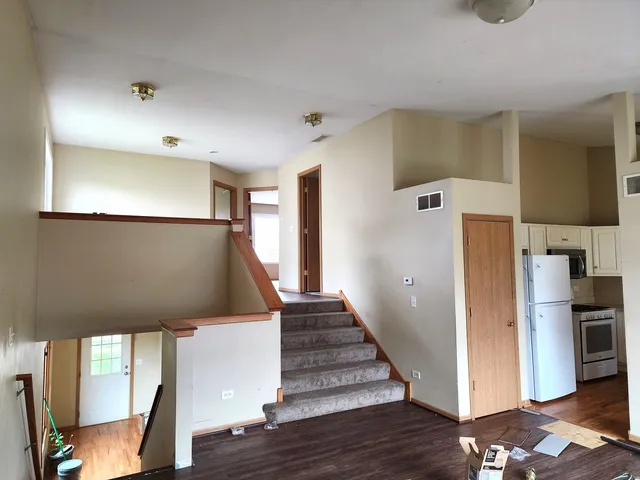 a view of a hallway with stairs and wooden floor