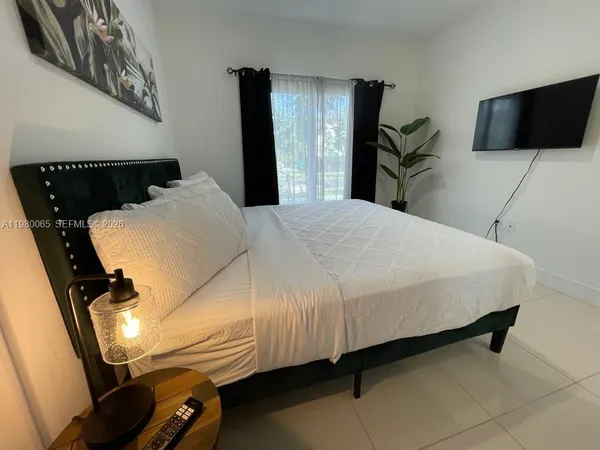 a bedroom with a bed and a flat tv screen on the dresser