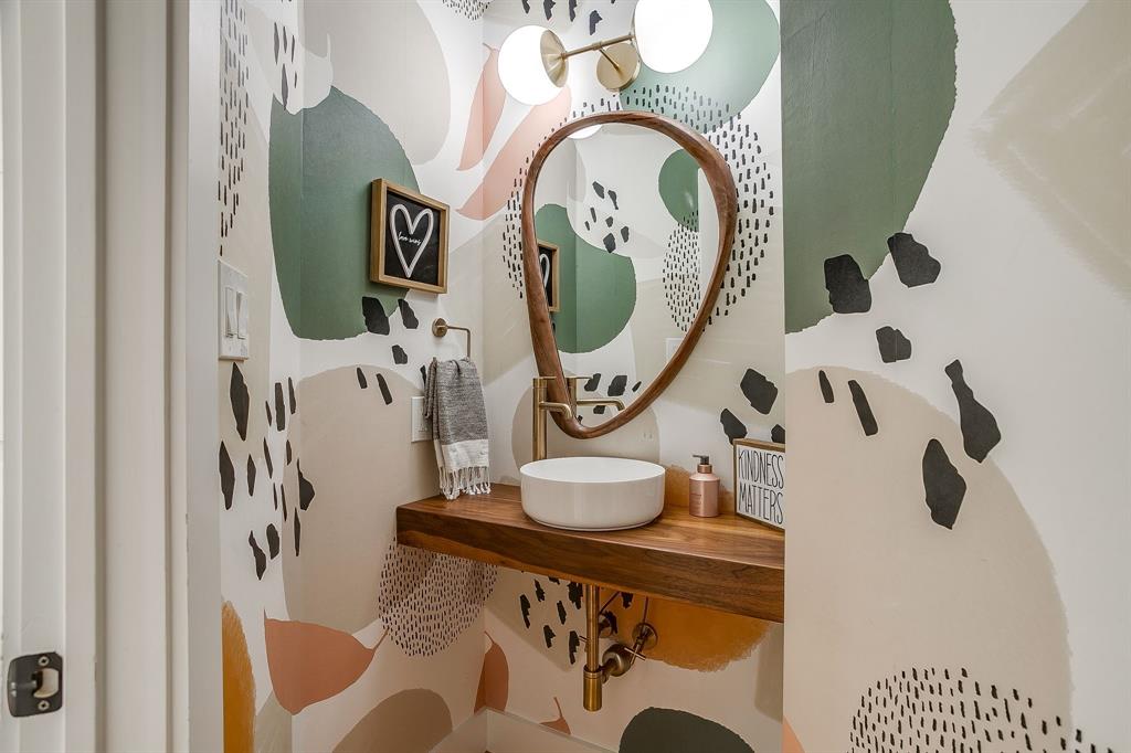 6700 Fortune Road Fort Worth, TX 76116 - Photo 23 of 40 Powder room featuring contemporary abstract wall covering, a floating wood vanity with a vessel sink, a gold-toned wall-mounted faucet, and a decorative mirror with a wood-finish frame