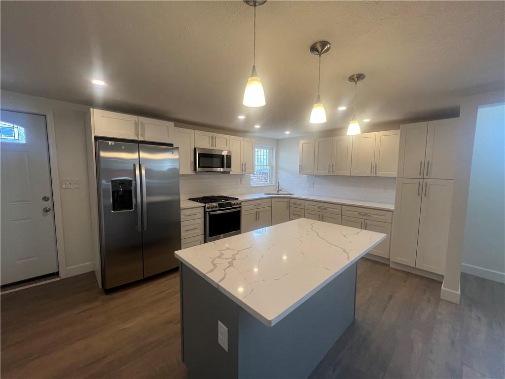 566 Merchant Street, Unit 1 Ambridge, PA 15003 - Photo 2 of 8 a kitchen with a refrigerator a sink dishwasher and a stove top oven with wooden floor