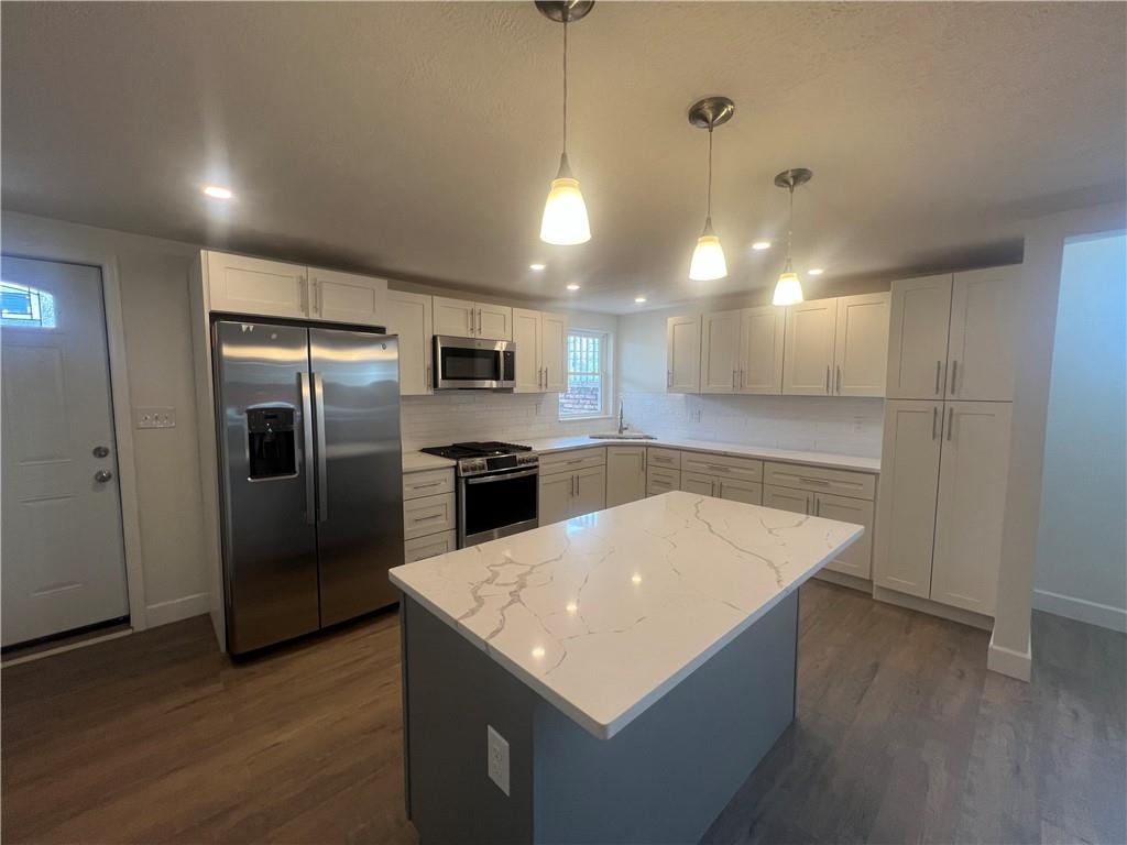 566 Merchant Street, Unit 1 Ambridge, PA 15003 - Photo 7 of 8 a kitchen with a refrigerator a sink dishwasher a oven and a dining table with wooden floor