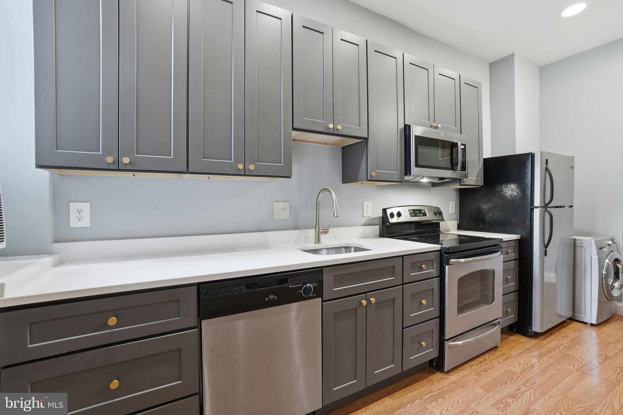 1440 Fairmont Street Northwest, Unit 3 Washington, DC 20009 - Photo 5 of 21 a kitchen with stainless steel appliances granite countertop a sink a stove a refrigerator and cabinets with wooden floor