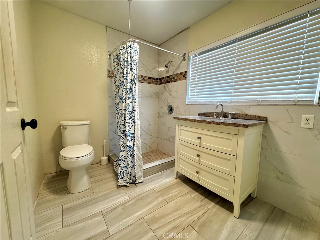 2775 Duncan Road Phelan, CA 92371 - Photo 17 of 29 a bathroom with a granite countertop toilet a sink and a mirror