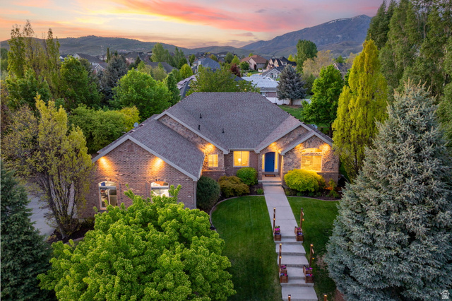 6208 West Bull River Road Highland, UT 84003 - Photo 72 of 90 Brick and stone facade residence featuring a prominent blue entry door, a gabled roofline, and established landscaping
