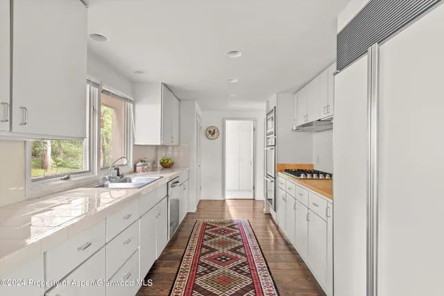 a large white kitchen with a sink and windows