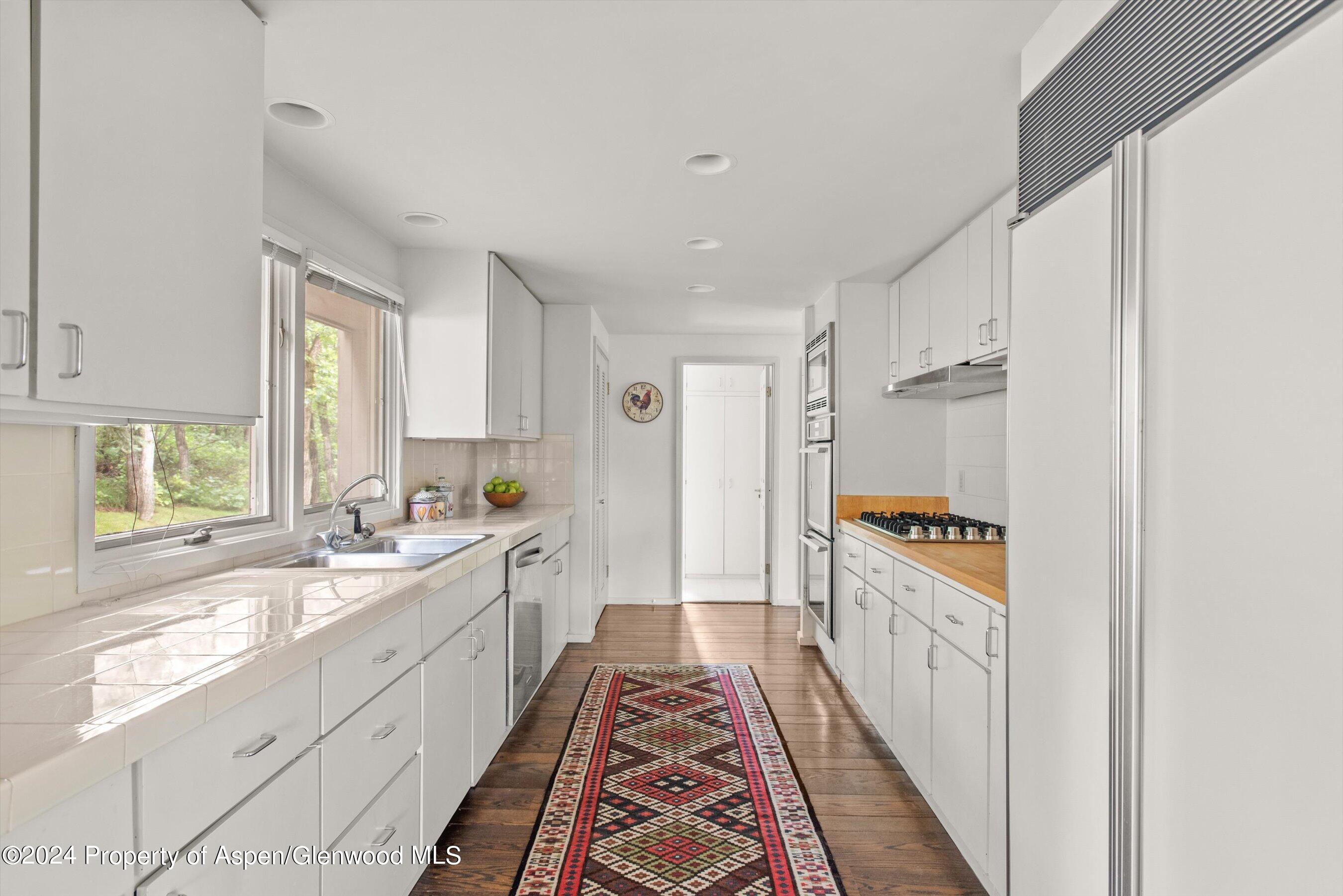 209 Larkspur Lane Aspen, CO 81611 - Photo 22 of 45 a large white kitchen with a sink and windows