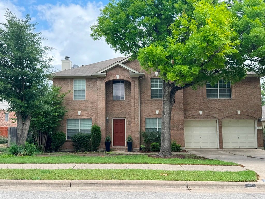 1009 Rutgers Drive Pflugerville, TX 78660 - Photo 1 of 3 Traditional home featuring concrete driveway, an attached garage, brick siding, and a chimney